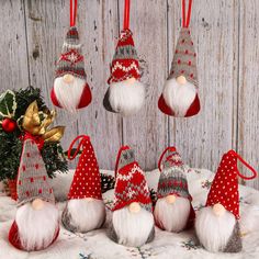 several gnome ornaments hanging from red and white christmas decorations