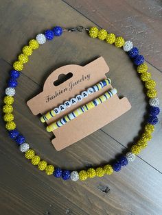 a yellow and blue beaded necklace on a wooden floor with a tag attached to it