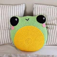 a green frog pillow sitting on top of a bed