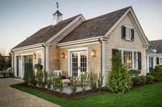 a small house with white trim and shingles on the roof is shown at dusk