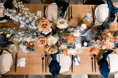 the table is set with blue and white napkins, silverware, and flowers