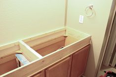 an unfinished bathroom vanity with drawers and toilet paper dispenser in the corner