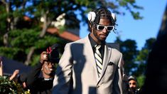 a man in a suit and tie with headphones on his ears walking down the street