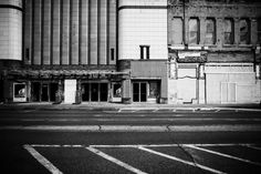 black and white photograph of an empty street in front of a large building with tall windows