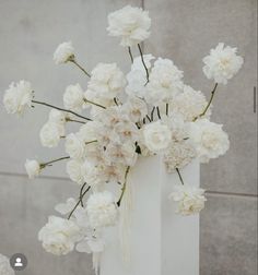 a white vase with flowers in it sitting on a table