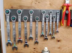 a bunch of tools are hanging on a wooden wall next to a bottle opener and screwdrivers