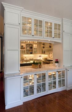 a large kitchen with white cabinets and wood flooring in an open concept area that is well lit