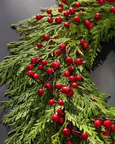 a christmas wreath with red berries and pine needles on a black surface, ready to be decorated