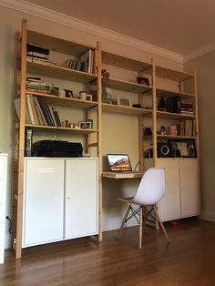 a white chair sitting in front of a book shelf filled with books and other items