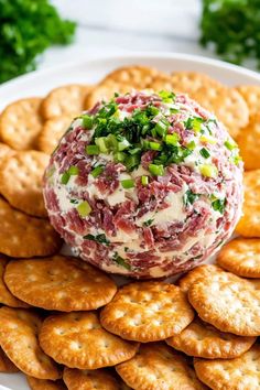 a cheese ball is on top of crackers and garnished with green onions