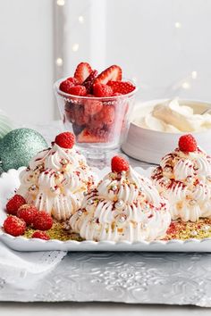 three desserts on a white plate with strawberries and whipped cream in the background