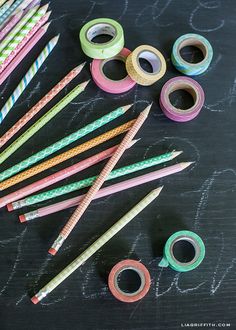 many different colored pencils and tape on a blackboard