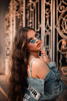 a woman with long hair wearing sunglasses and denim jacket