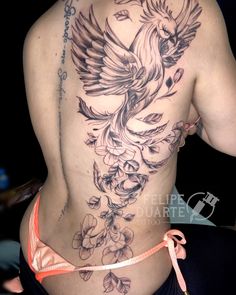 the back of a woman's body with flowers and birds tattoo on her side