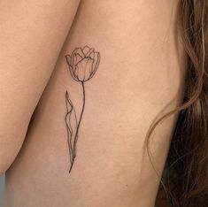 a woman's thigh with a single flower tattoo on her left side ribcage