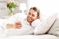 a man laying in bed looking at his cell phone