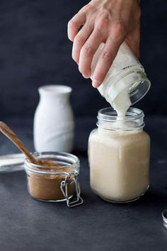 a person pouring something into a glass jar