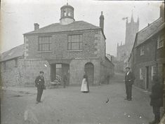 an old black and white photo of people standing in front of a building with a clock tower