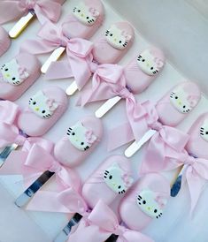 hello kitty cake pops with pink bows and bowknots are arranged in a box