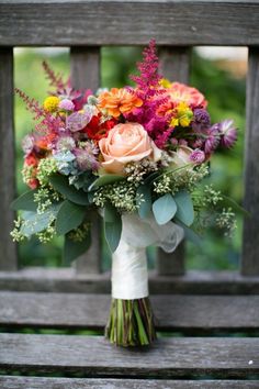 a bouquet of flowers sitting on top of a wooden bench