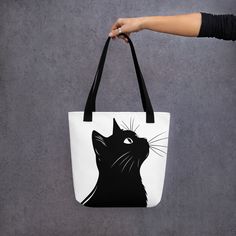 a woman holding a black and white cat tote bag