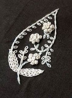 an embroidered piece with white flowers and leaves