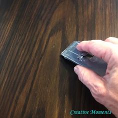 a hand holding a mouse on top of a wooden table