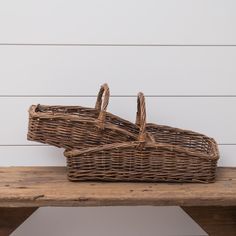 two wicker baskets sitting on top of a wooden bench next to a white wall