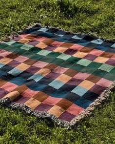 a multicolored blanket laying on the grass