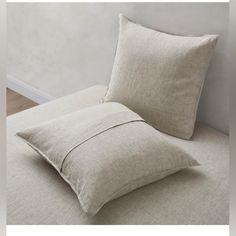 a white pillow sitting on top of a bed next to a wall