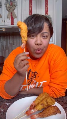 a young man holding up two skewers of food