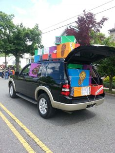 an suv with boxes on the back is parked in front of a building and people are walking by