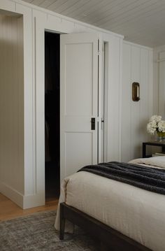 a bed sitting in a bedroom next to a tall white closet with doors on each side