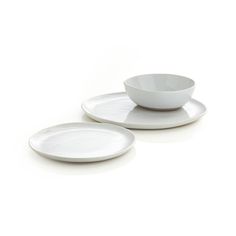 two white plates with saucers sitting on top of each other in front of a white background