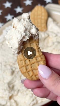 a person holding up a waffle cone with whipped cream on top in front of a bowl of food