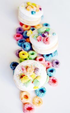 there are many different colored donuts on the white table with sprinkles