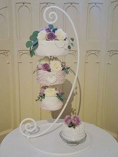 three tiered wedding cake with flowers on the top and bottom, sitting on a table