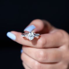 a woman's hand holding an engagement ring with a diamond in the middle, on a black background