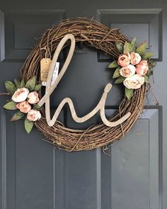 a wreath with the letter h on it and flowers hanging from it's front door