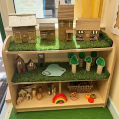 a display case filled with lots of small houses and trees on top of green grass