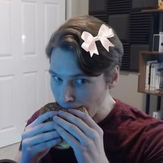 a man eating a doughnut with a bow on it's head while sitting in front of a table