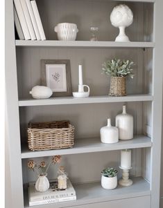 a white bookcase filled with books and vases