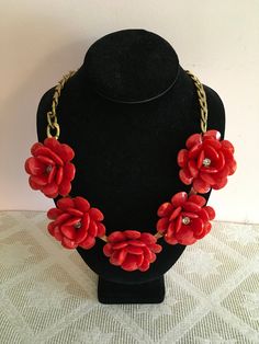 "This bold necklace consists of five large flower blossoms made of layers of faceted red tear-drop petals. The petals are made of plastic and surround rhinestones centers. A large, flat gold chain is attached at each end of the necklace and it fastens with a spring ring clasp. There is also a smaller chain attached on one end making the piece adjustable in length. A gold tag near the end says, \"ILY.\" Materials: Plastic beads Rhinestones Gold tone metal hardware Measurements: Necklace length - 24\" Flower diameter - 2 1/2\" This necklace is in good, used condition with light wear on the metal." Elegant Red Flower Necklace With Charm, Red Flower-shaped Jewelry For Summer, Red Jewelry With 3d Flower Details, Red Flower-shaped Jewelry For Spring, Red Flower-shaped Necklace For Gifts, Gold Tag, Red Flower-shaped Necklace With Rose Design, Flower Statement Necklace, Bold Necklace