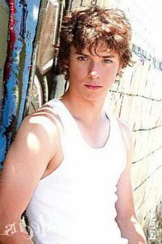 a young man leaning against a wooden fence