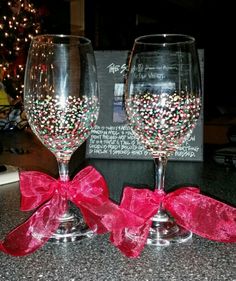 two wine glasses with red bows are sitting on a counter