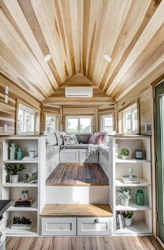 the interior of a tiny home with wood floors and white walls, built in shelving