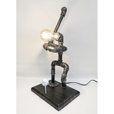 the lamp is made out of pipes and has a light bulb on top of it