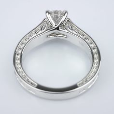 a white gold engagement ring with a princess cut diamond in the center and filigrees on the sides