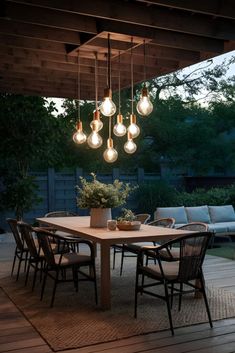 an outdoor dining area with lights hanging from the ceiling and chairs on the floor below