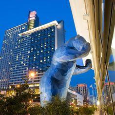 a large blue elephant statue in front of a tall building at night with lights on